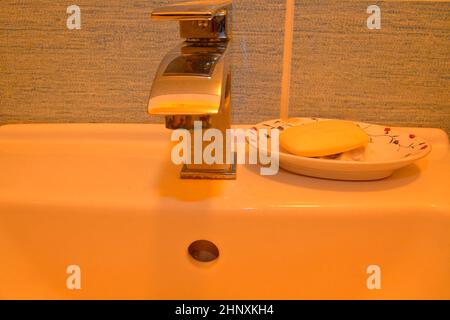 Modern faucet and classic soap dish on white basin. Minimalist concept. Stock Photo