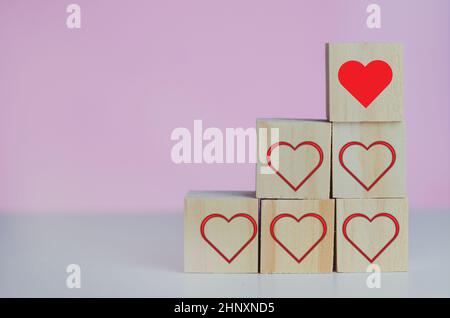 Wooden cubes with love  symbol heart red on the pink background and copy space. Stock Photo
