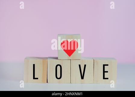 Wooden cubes with love  symbol heart on the pink background and copy space. Stock Photo