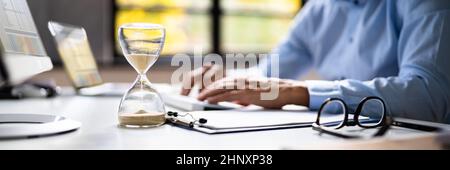 Late Invoice And Billing Deadline With Hourglass At Desk Stock Photo