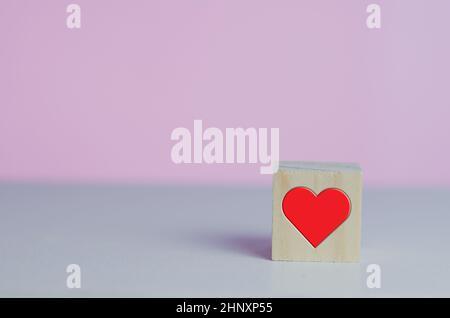 Wooden cubes with love  symbol heart red on the pink background and copy space. Stock Photo