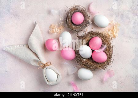 Easter background with pink and white eggs and an Easter bunny from a napkin on a light pink background. The concept of a Happy Easter. Stock Photo