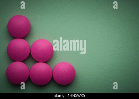 Pink pills laid out on a green background Stock Photo