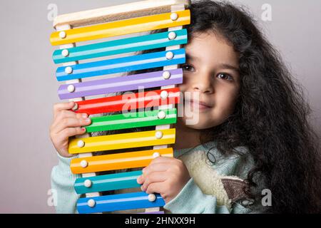 Little girl portrait with xylophone in hand looking in camera with expression, childhood memories Stock Photo