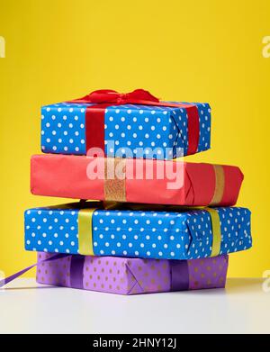 a stack of gift boxes tied with a ribbon on a yellow background Stock Photo