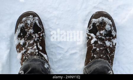 Male legs in snow-covered winter boots, top view. Winter walk in the snow. Focus on your legs. Beautiful white winter weather with fresh snowfall Stock Photo
