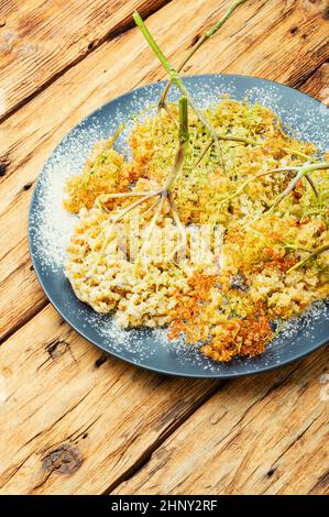 Fried elderflower in batter with powdered sugar. Spring flower dessert Stock Photo