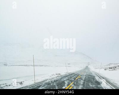 Driving through blizzard snowstorm on black ice and snowy white road ...