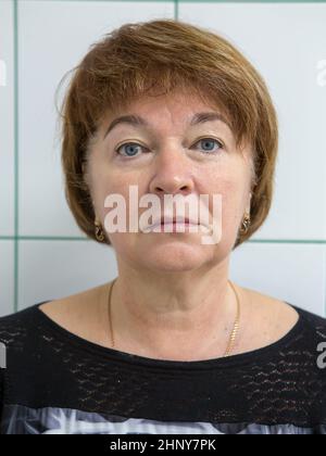 An adult Caucasian woman with blond short hair, a lancy jacket against the background of white tiles. At the reception at the cosmetologist before the Stock Photo