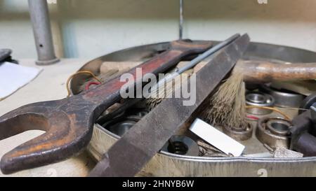 Work tools on the board and in the workshop. Workshop scene. A lot of old tools on a dirty desktop. The concept of carpentry and painting Stock Photo