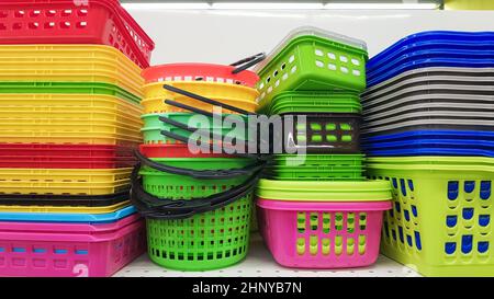 Multi-colored plastic containers of different shapes and sizes with and without lids, stacked in a pile on a store window. Sale of boxes for storage a Stock Photo