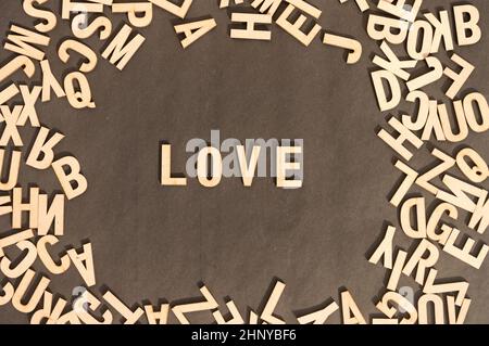 Love Word In Wooden Cube Alphabet Letters Top View On A rustic paper Background. Stock Photo