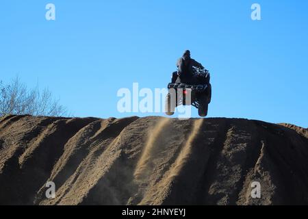 silhouette of a man jumping with a quad against a blue sky. Stock Photo