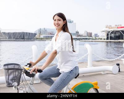 Young woman riding bike in city park Stock Photo