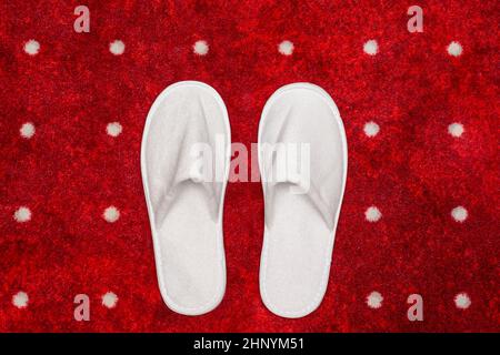 White slippers on red carpet with white dots background Stock Photo