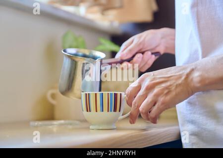 Close-up of a woman's hands preparing coffee in an iron cezve. Stock Photo
