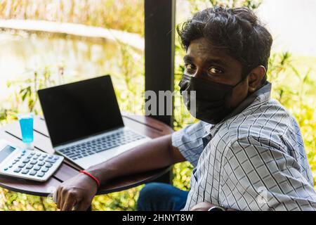 Happy Asian hand black man person sitting working with laptop computer, device technology and connecting networking online at the coffee cafe shop Stock Photo