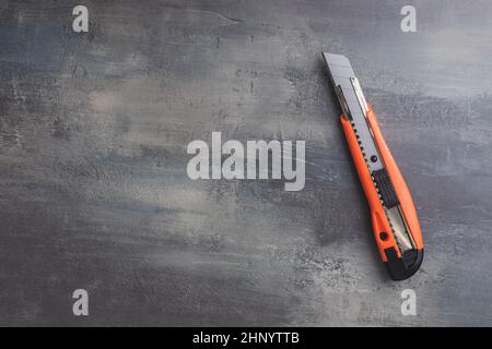 Plastic orange utility knife on table. Top view. Stock Photo
