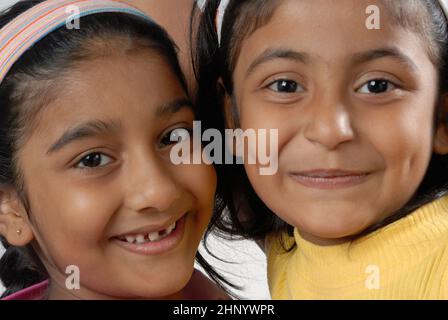 India May 05 2008  Indian Playful and pretty little sisters or friends in playful mood; hugging; kissing each other. Isolated over white background. Stock Photo