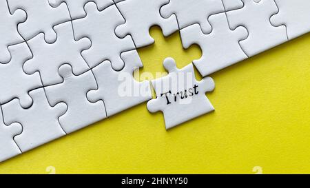 Trust word on a jigsaw puzzle with yellow background. Stock Photo