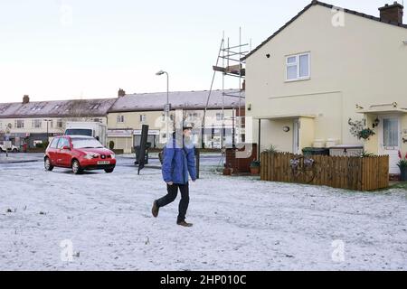 A person walking in fresh snowfall in Colburn, North Yorkshire, as Storm Eunice sweeps across the UK after hitting the south coast earlier on Friday. With attractions closing, travel disruption and a major incident declared in some areas, people have been urged to stay indoors. Picture date: Friday February 18, 2022. Stock Photo