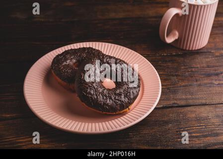 Two Chocolate Donuts and Mug of Hot Chocolate with Marshmallow on Rustic Wooden Surface Stock Photo