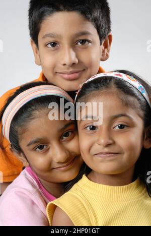 India May. 05, 2008 - Playful and pretty Indian Asian little brother and two sisters or friends in playful mood, hugging, dancing each other. Stock Photo