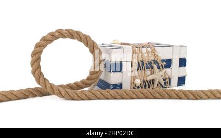 Thick rope next to blue and white striped box chest covered with fishing net, decorated with starfish and shells. Marine theme still life isolated on Stock Photo
