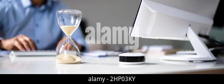 Late Invoice And Billing Deadline With Hourglass At Desk Stock Photo