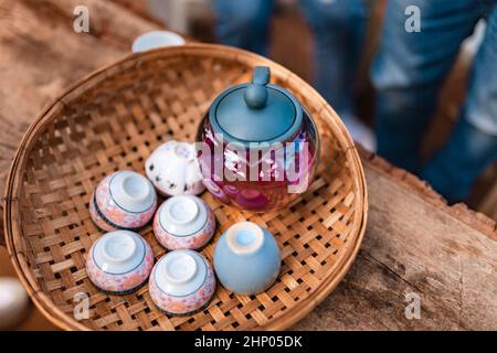 Teapot and tea cups on rattan at home. Stock Photo