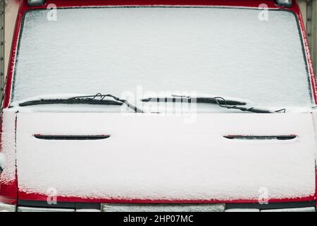 The windshield of the car covered with snow. Windscreen wipers are like eyebrows above the eyes. Stock Photo