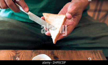 Man spreading butter on the bread with Pan Fried Egg with Toppings Stock Photo