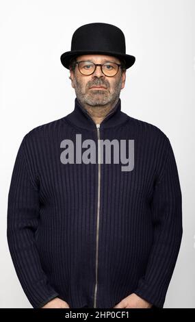 Portrait middle aged man with glasses, bowler hat and round glasses. He is wearing a dark jumper. Isolated on white background Stock Photo