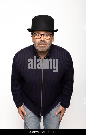 Portrait middle-aged man with glasses, bowler hat and round glasses, is leaning forward. Isolated on white background Stock Photo