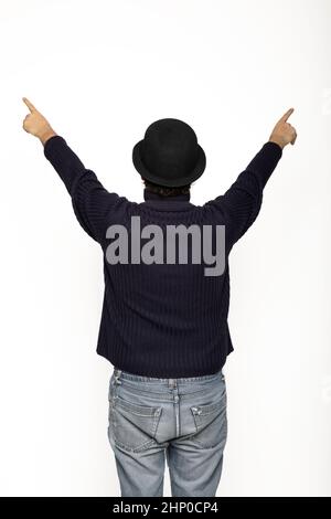 Man from behind rejoices with his arms up. He is wearing a blue sweater, jeans and a bowler hat. Isolated on white background Stock Photo