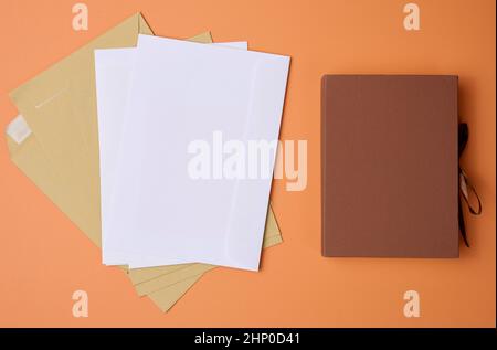 stack of white envelopes on orange background, top view Stock Photo