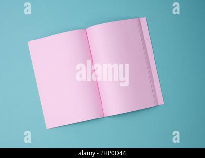 open notebook with blank pink sheets on blue background, top view Stock Photo