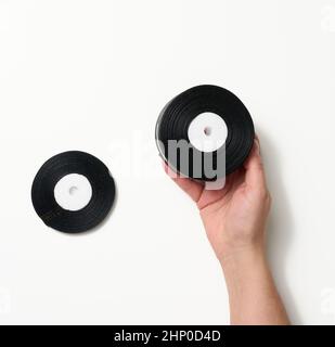 female hand holding rolled up black silk ribbon on white background Stock Photo