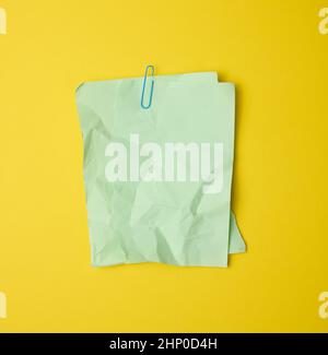 rectangular crumpled blank green sheet of paper on yellow background Stock Photo