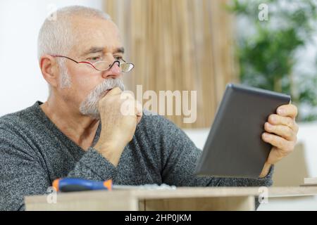 waist up portrait of senior carpenter using tablet Stock Photo