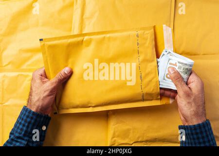 Male hands packing money in bubble envelopes for shipping. Stock Photo
