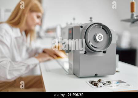 Seamstress works on sewing machine at her workplace in workshop. Dressmaking occupation, handmade tailoring business, handicraft hobby Stock Photo