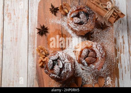 Baked apples with nuts and raisins. Homemade baked apples in the oven, with sugar powder close-up. Holiday dessert Stock Photo