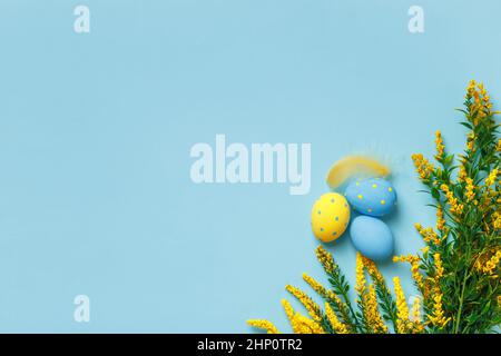 Top view of easter eggs and spring flower twigs on blue background. Flat lay with space for text and copy space Stock Photo