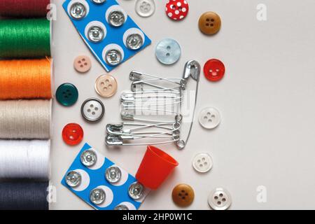 Multicolored bobbins thread buttons pins on the table. Flat lay closeup with copy space. Stock Photo