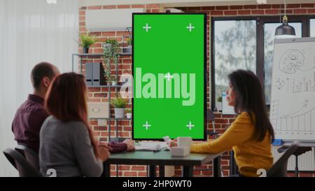 Employees using green screen on monitor vertically in boardroom, meeting to discuss ideas. Business people working with isolated mockup template and blank copy space for chroma key background. Stock Photo