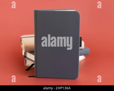Stack of beige and grey hardcover notebooks isolated on red closeup. Textbook mockup, planner cover with place fot text. Educational, business and org Stock Photo