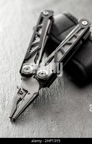 Multi-tools pliers with other tools and knife. Multifunction pliers on stone table. Stock Photo