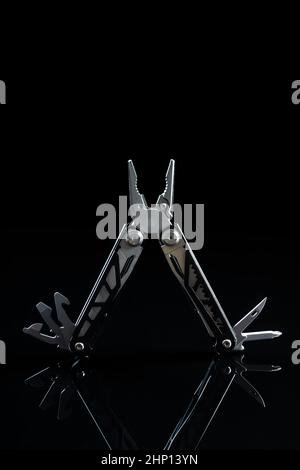 Multi-tools pliers with other tools and knife. Multifunction pliers on black background. Stock Photo