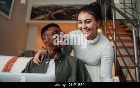 Biracial couple working at apartment on laptop Stock Photo